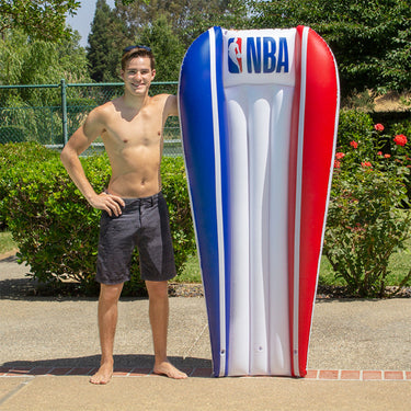 74.5” L x 44” W (deflated) NBA Poolmaster mattress float. blue striped on one side red striped on the other side and otherwise white with the NBA Logo on the pillow. Man standing next to it for scale.