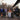Family sitting around a fire pit on a wooden deck with trees in the background