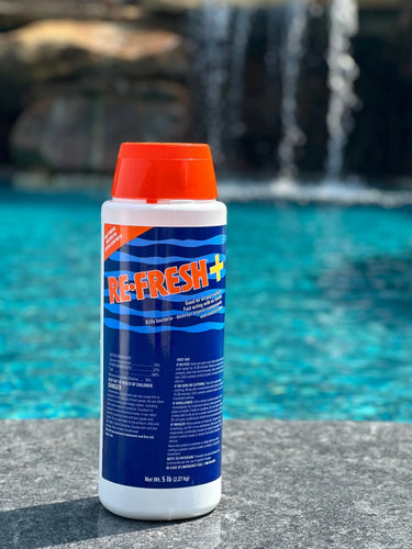 5lb container of pool shock on a concrete ledge beside a pool
