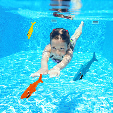 Shark Dive Toys. package of 3 with orange, blue and yellow shark. 6" long each. picture shown with young girl diving to retrieve shark dive toys