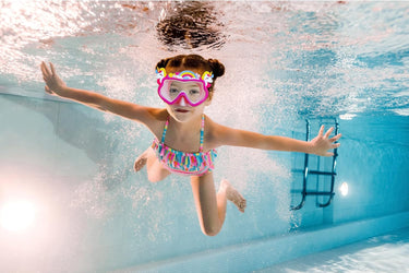 Little girl swimming underwater with the Unicorn themed face mask