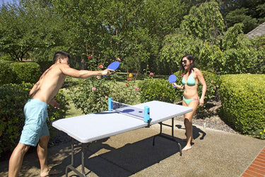 Play N Go Table Tennis - includes 2 blue paddles, 2yellow ping pong balls and a blue net that attaches to a plastic table. table not included - shown with a 2 teenagers, a boy and a girl playing the game.