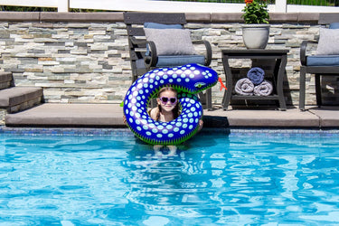 Child in water holding up the blue snake split ring float for size scale.