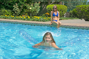 Mother watching daughter swim with 60″ Silver Glitter Noodle - Transparent with glitter inside, inflatable Noodle to float on.