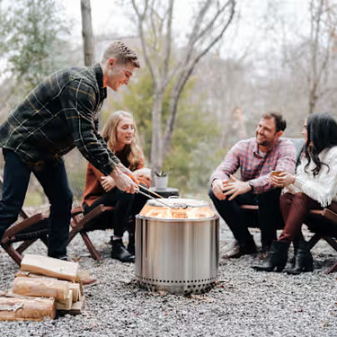 Group of people gathered around a campfire in a forest setting