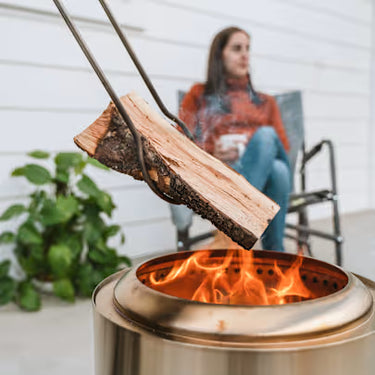 Person using a metal fire pit with flames, blurred background