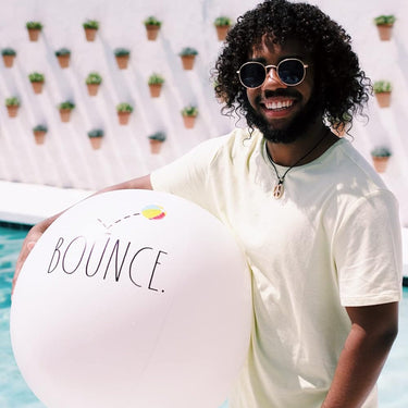 Man holding Jumbo White Beach Ball with Bounce in text, standing by a pool